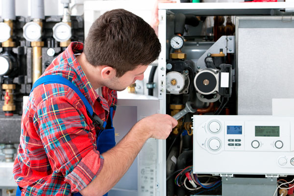 HVAC technician inspecting and repairing boiler controls in Goodyear